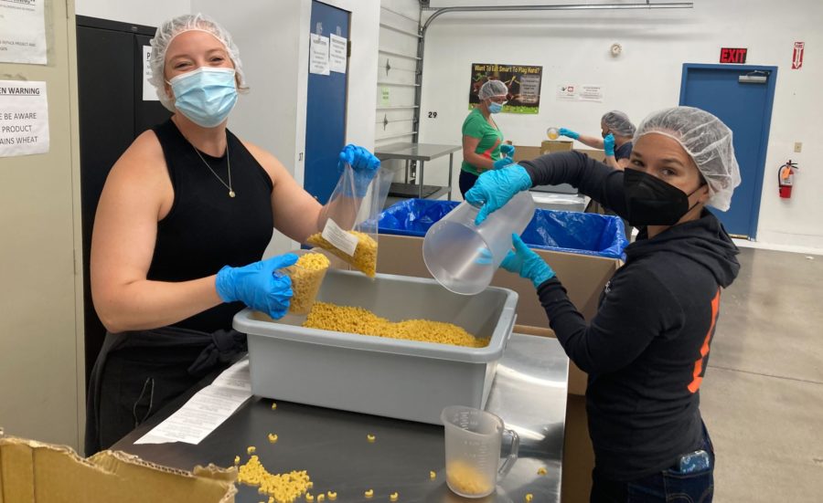 Dos participantes en el programa voluntario de empleados de Submittable reparten pasta en el banco de alimentos de Missoula