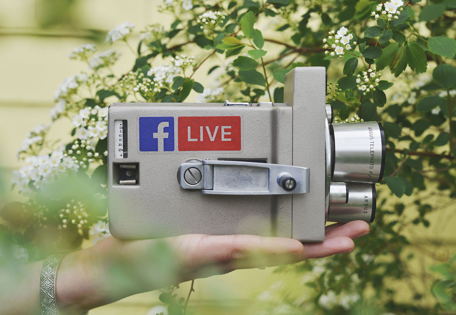 Facebook çıkartması olan eski bir video kamerayı tutan bir el