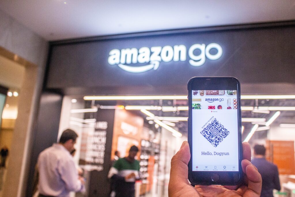 Tangan memegang telepon di luar toko Amazon Go