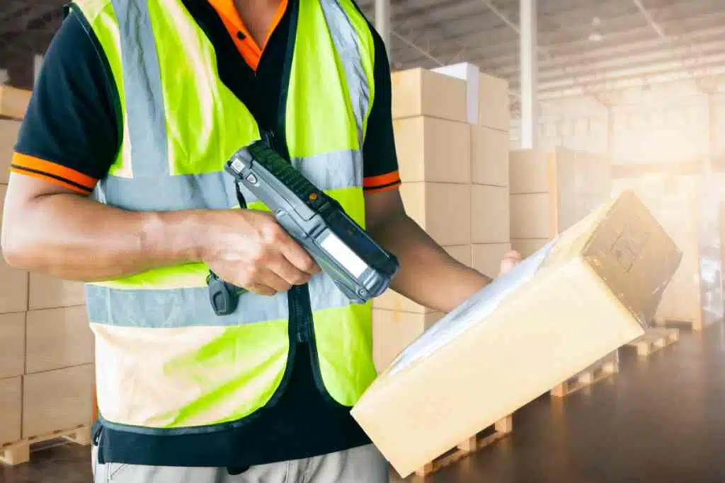 bir barkod tarayıcı ve envanter tarama yazılımı kullanan bir depo çalışanı