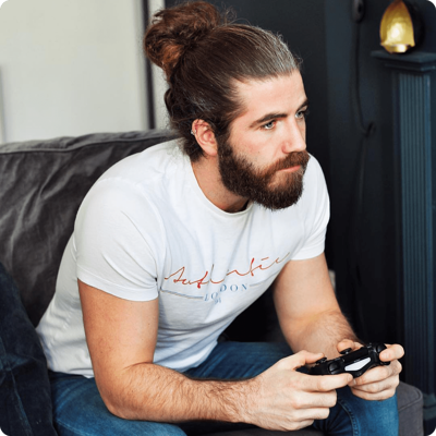 Un homme barbu joue intensément à des jeux vidéo