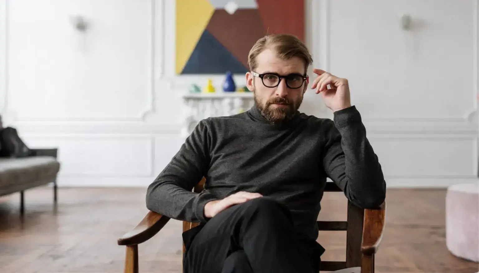 uomo in maglione nero seduto su una sedia di legno marrone