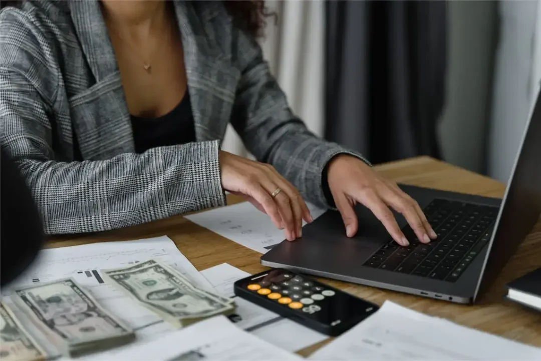 Frau-vor-Laptop-und-fast-haufenweise-Geld