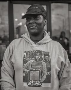 Czarno-białe zdjęcie Kartishy Henry w bluzie z kapturem i czapce baseballowej
