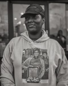 Imagen en blanco y negro de Kartisha Henry con una sudadera con capucha y una gorra de béisbol.