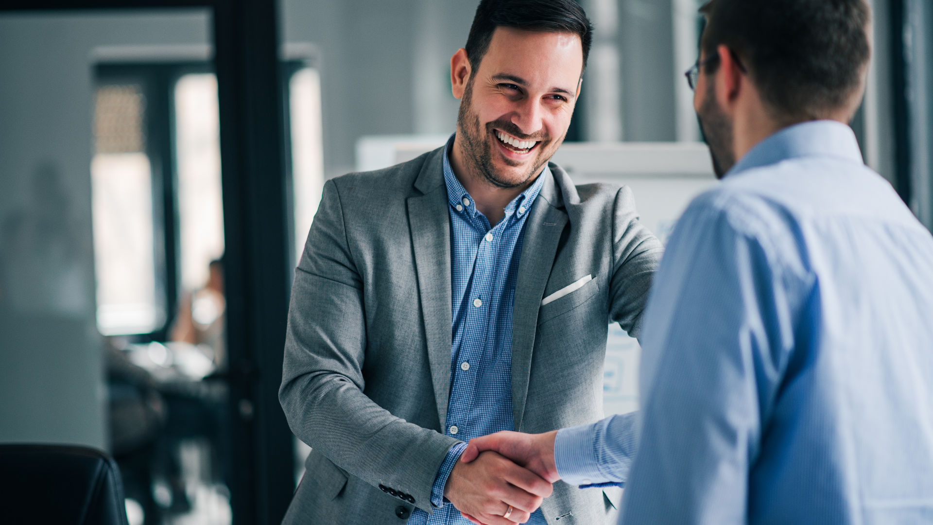 ชาย 2 คนในชุดสูทกำลังจับมือกัน