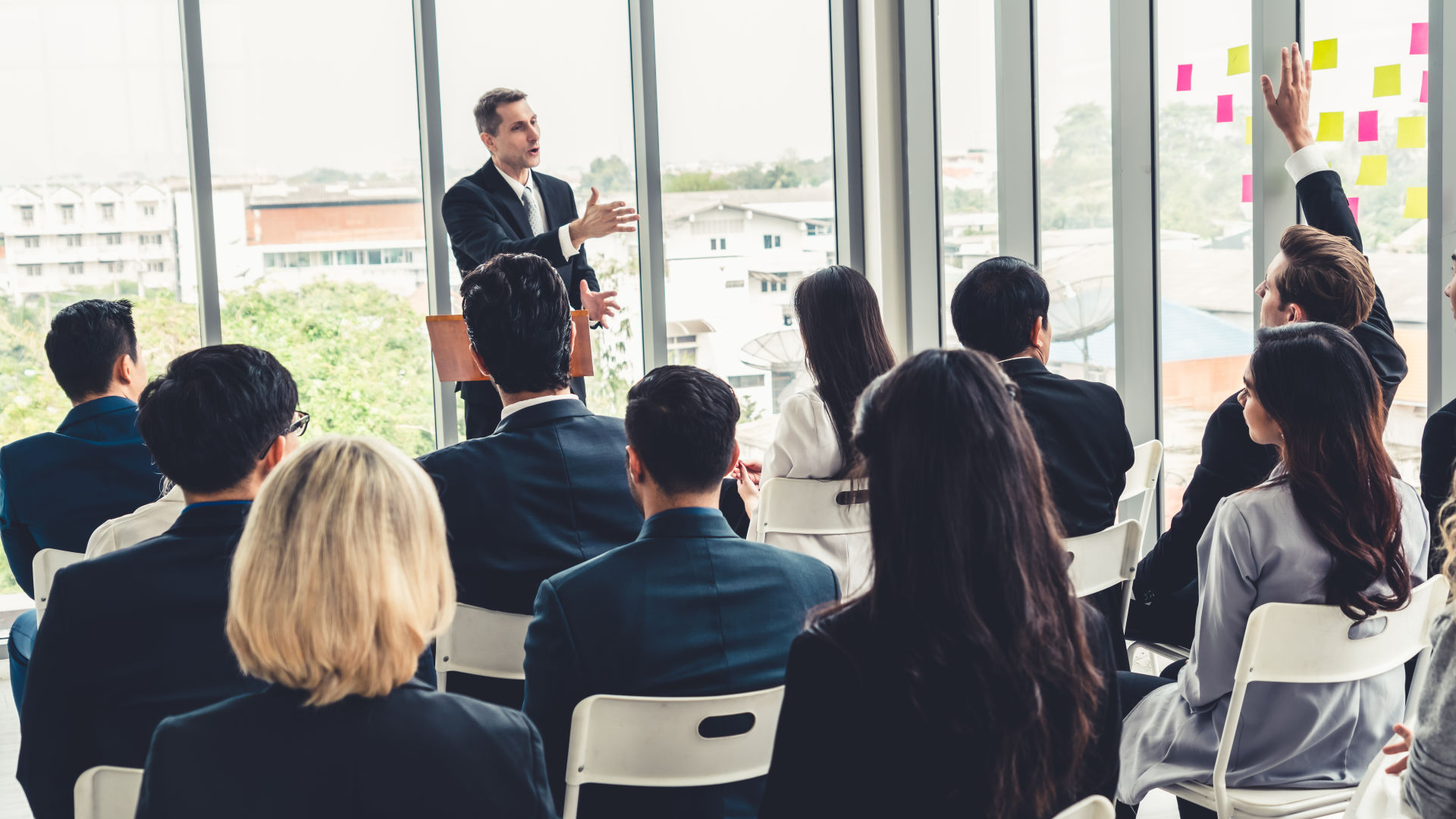 นักธุรกิจกลุ่มหนึ่งนั่งฟังผู้ชายบนเวที