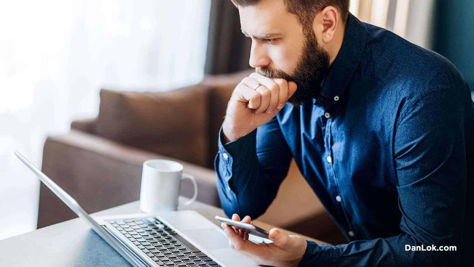 Dizüstü bilgisayar ve telefon ile harcamalarını analiz eden adam